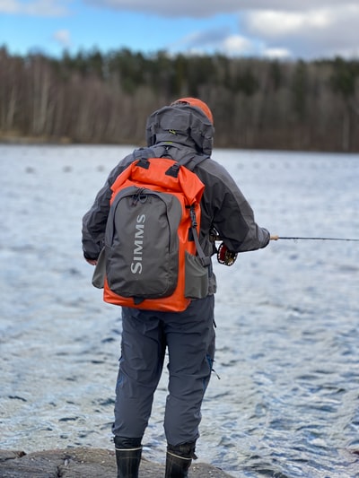 Dressed in a black and orange jacket and black pants with black and white rod
